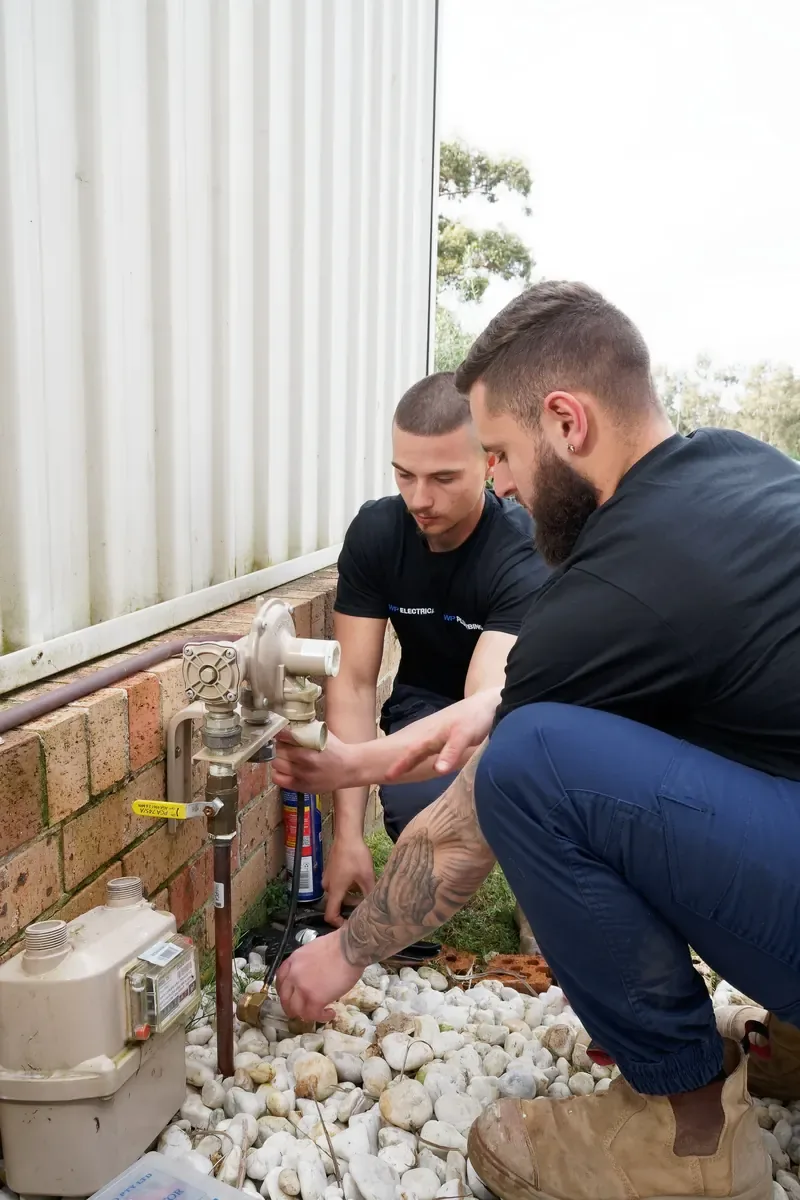 Two WP Electrical electricians in branded shirts checking a meter