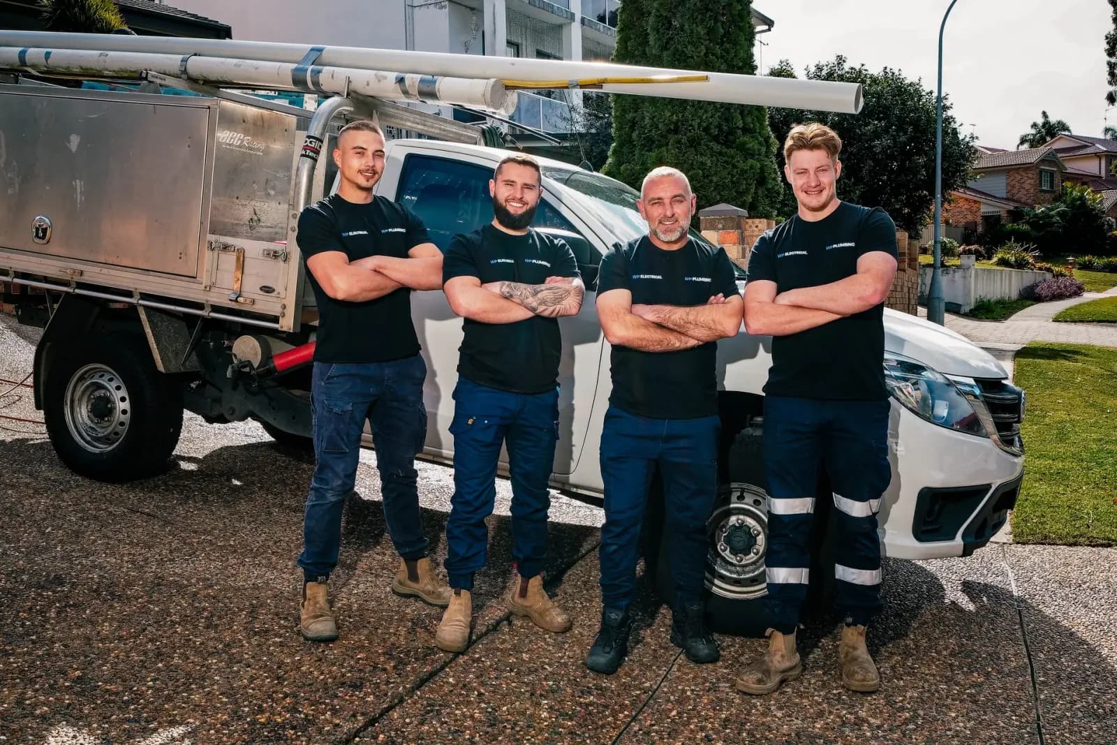The WP Electrical team in branded shirts beside a work ute